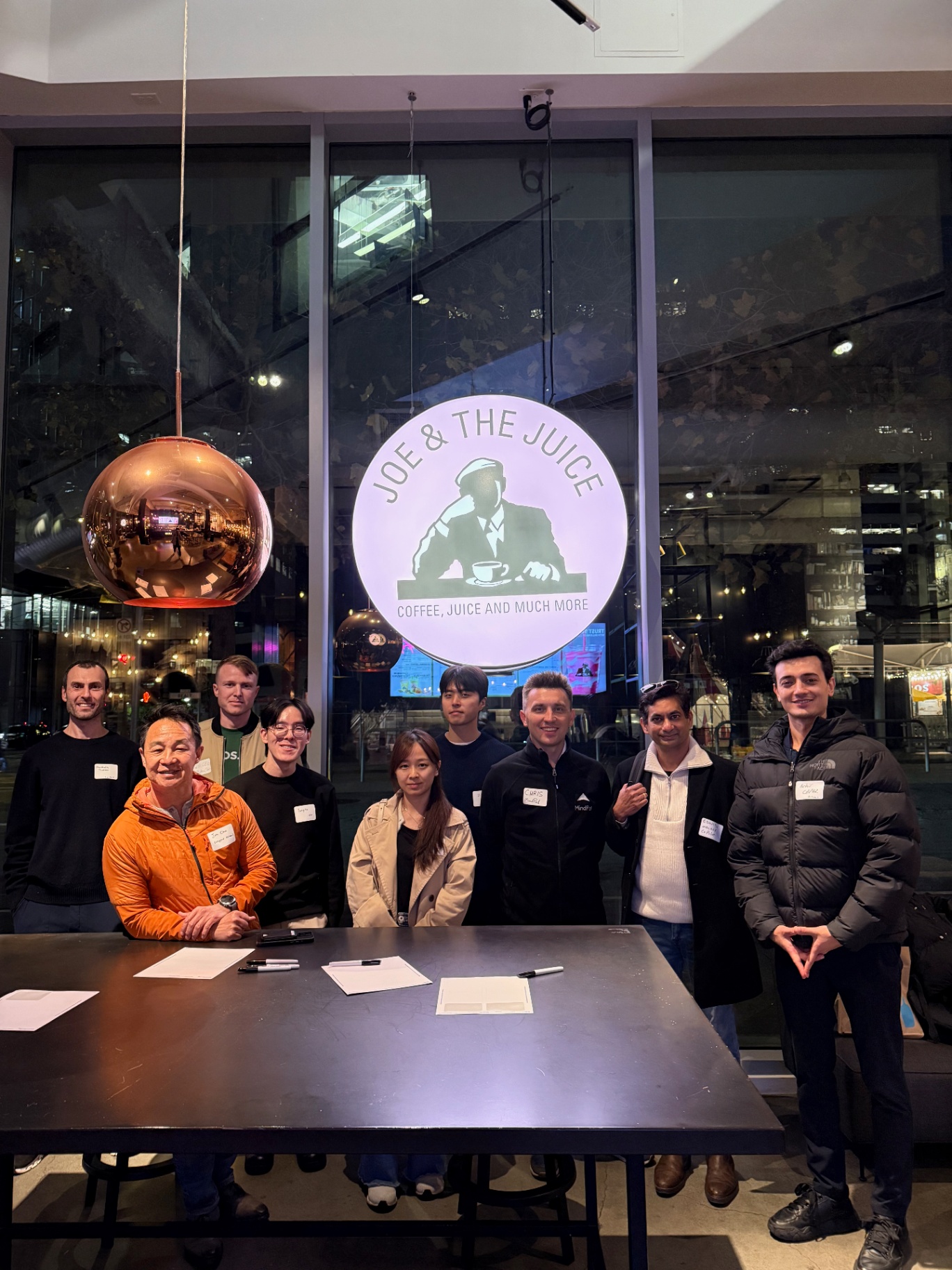 Founders posed under the Joe & The Juice sign at night