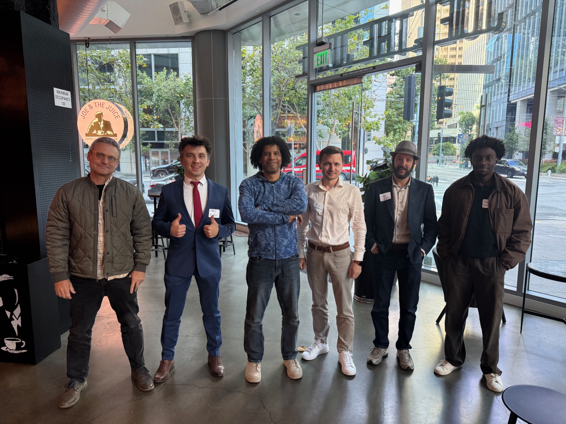 Six founders in front of floor-to-ceiling windows